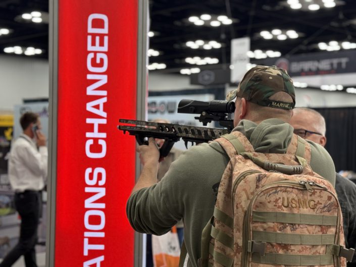 Man wearing marine backpack trying out a crossbow at the Killer Instinct booth - ATA Show